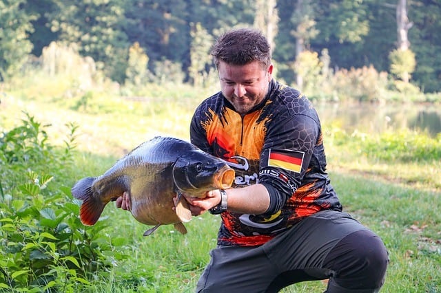 A photo of a fisherman holding a carp, taken with Canon Rebel t6i camera.