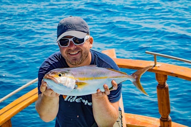 A photo of an angler holding a tuna fish, taken with Canon Rebel T6i.